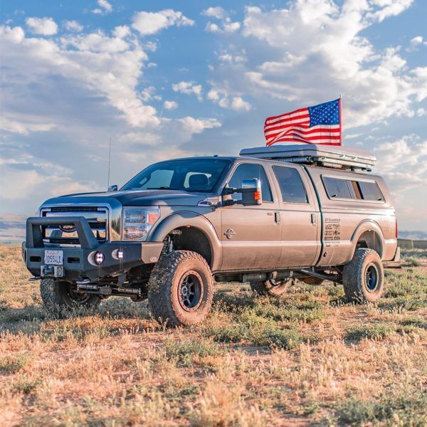 Custom trucks and vans build featuring SnugTop camper shell, roof rack, and American flag