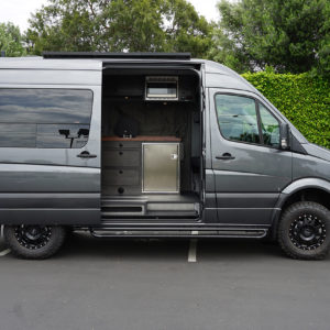 Customized Adventure and Travel Sprinter Van with Fiamma Awning, side steps, Custom Cabinets over Stainless Steel Refrigerator.