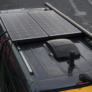 Upfitted van with ladder rack, solar power system, and retractable awning.