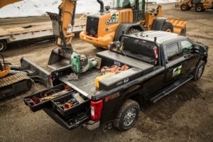 Truck at construction site equipped with DECKED CargoGlide Truck Bed System and DECKED Drawer System for organized, secure tool storage.