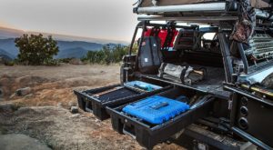 Overlanding rig with rooftop tent, open rear with DECKED drawers pulled out and adventure gear stowed.