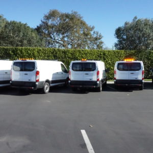 Upfitted fleet of five vans with Whelen lighting systems on top.