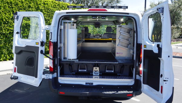 Customized van from our work trucks and vans lineup with drawers, shelves, paper dispenser, open rear doors, and exterior custom lighting.