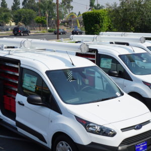 Fleet of three white Ford vans with roof-mounted tube carriers and interior shelving — part of our Work Trucks and Vans solutions.