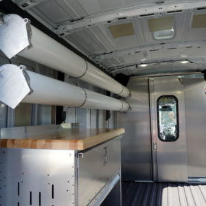 Upfitted cargo van with Ranger shelving, plumbing tubes, protective shield, and wood work surface.