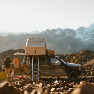 Overlanding truck with mounted Tepui tent and ladder deployed in rugged off-grid location.