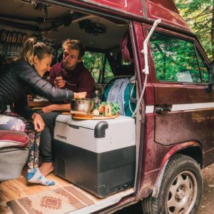 Cozy van interior with couple dining together, Dometic fridge built into custom kitchenette.