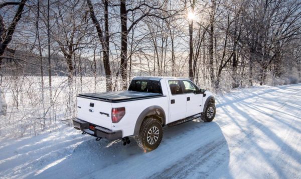 Extang Bed Cover on White Ford Raptor Truck Traveling on Snowy Road