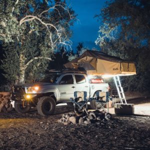 Adventure-ready truck with rooftop tent and RIGID LED lighting creating a cozy illuminated campsite.