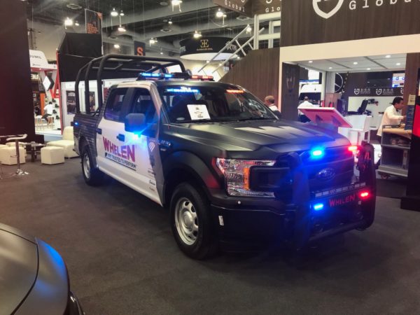 Police cruiser featuring Whelen emergency LED lights installed in the front grille.