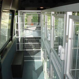 Van interior showing multiple secured cages for mobile dog pickup and daycare.