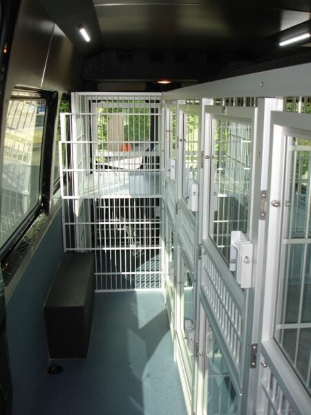 Van interior showing multiple secured cages for mobile dog pickup and daycare.