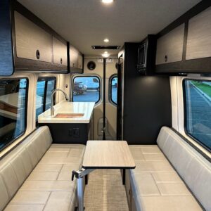 Custom camper van interior with fold-up table, galley, sofa bed, and rear kitchen setup.