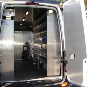 Plumber van interior setup with rear doors open showing shelving, overhead lighting, and finished door panels