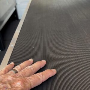 Close-up of ribbed rubber work surface on locksmith van upfit workbench with hand for scale
