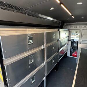 Locksmith van upfit interior showing workbench with rubber surface, overhead lighting, and closed cabinets
