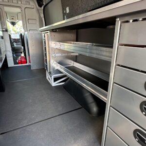 Low angle view of locksmith van upfit showing workbench drawers, shelving, and Sortimo partition toward front of van