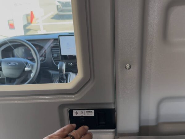 Hand operating the latch on a Sortimo ProPartition Light sliding door partition in a commercial van.