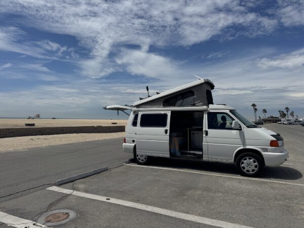 Front view of Gabby’s Volkswagen Eurovan with its pop-top raised near the beach